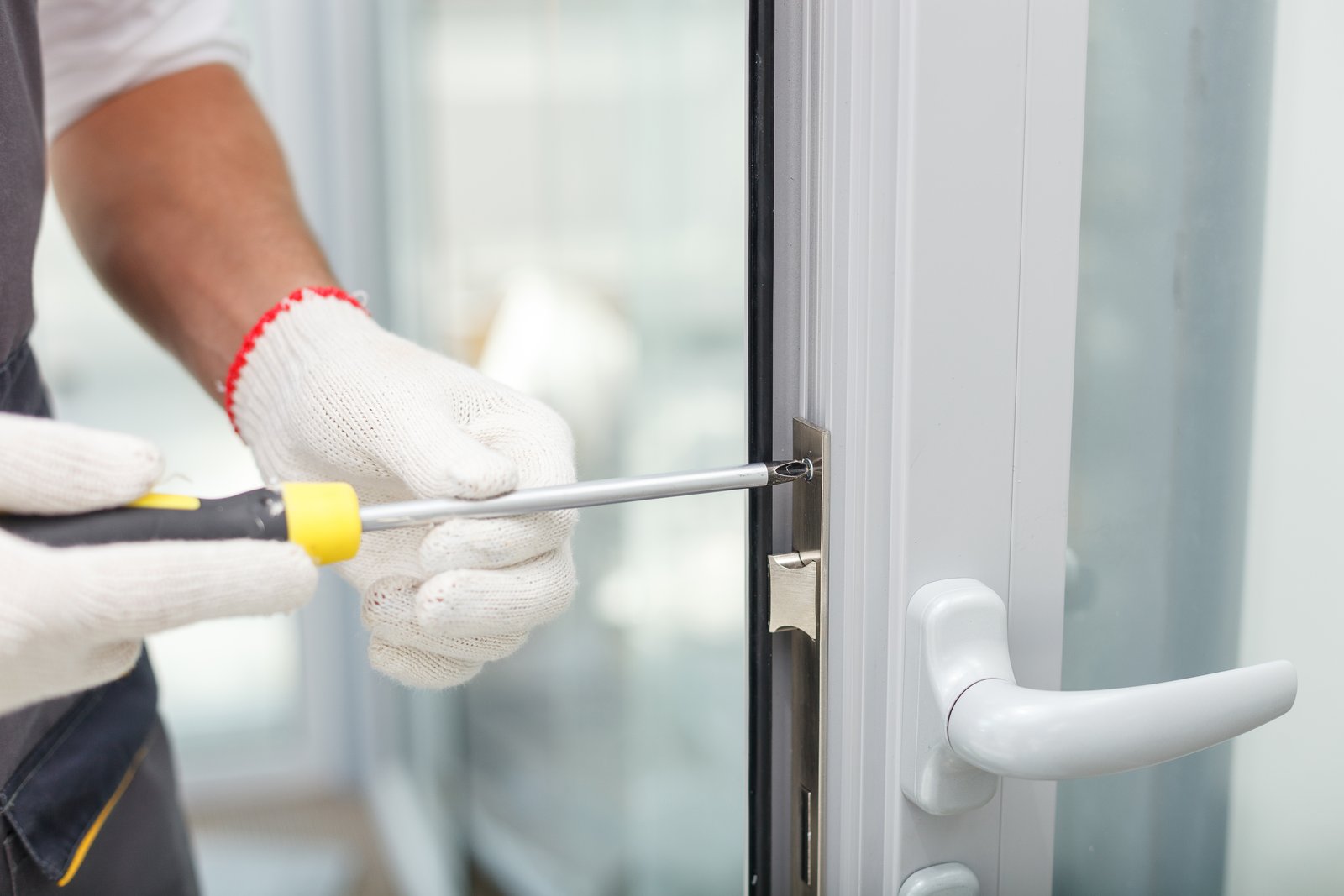 Gloved hands fitting a uPVC multipoint lock mechanism