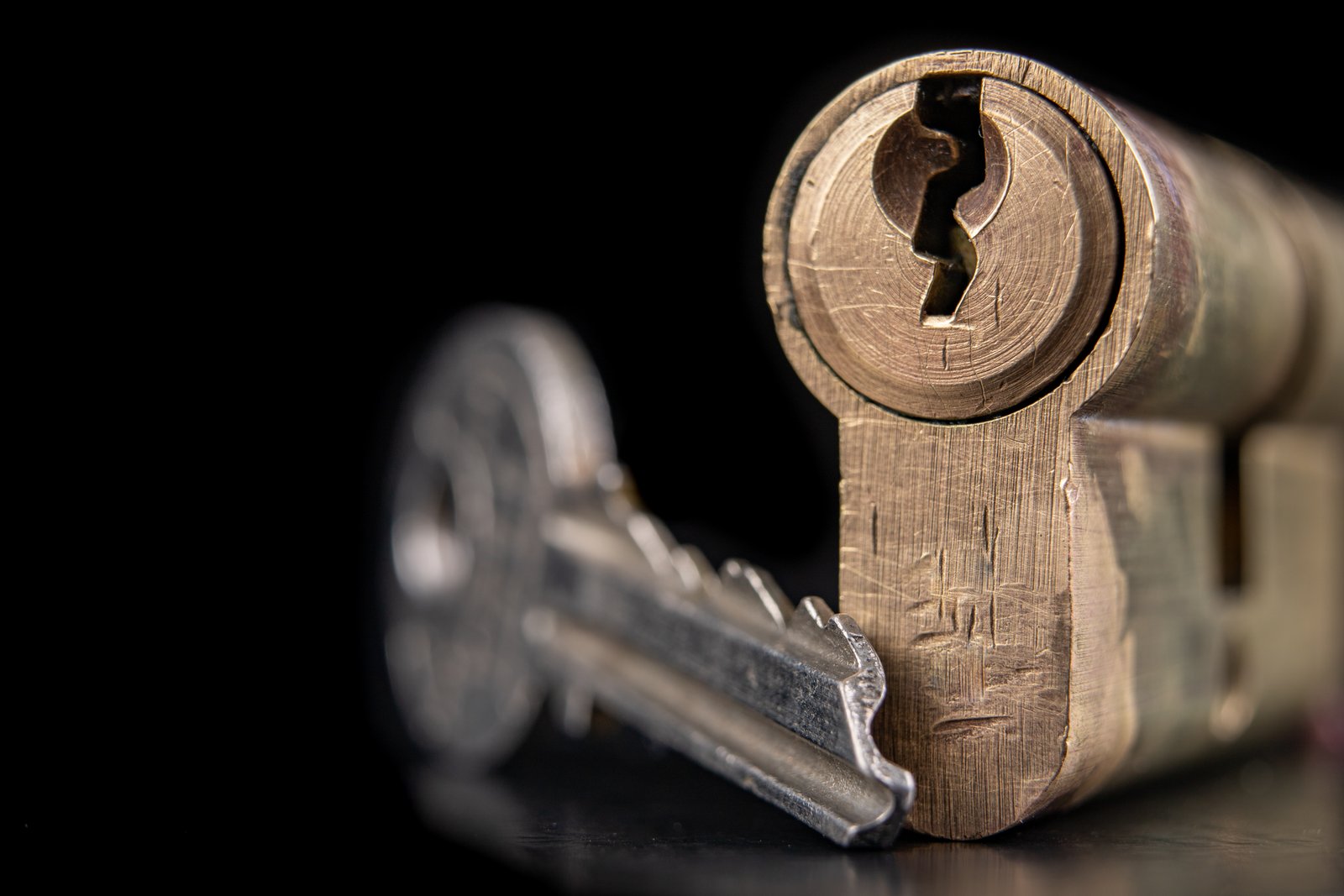 A worn cylinder lock photographed against a dark background