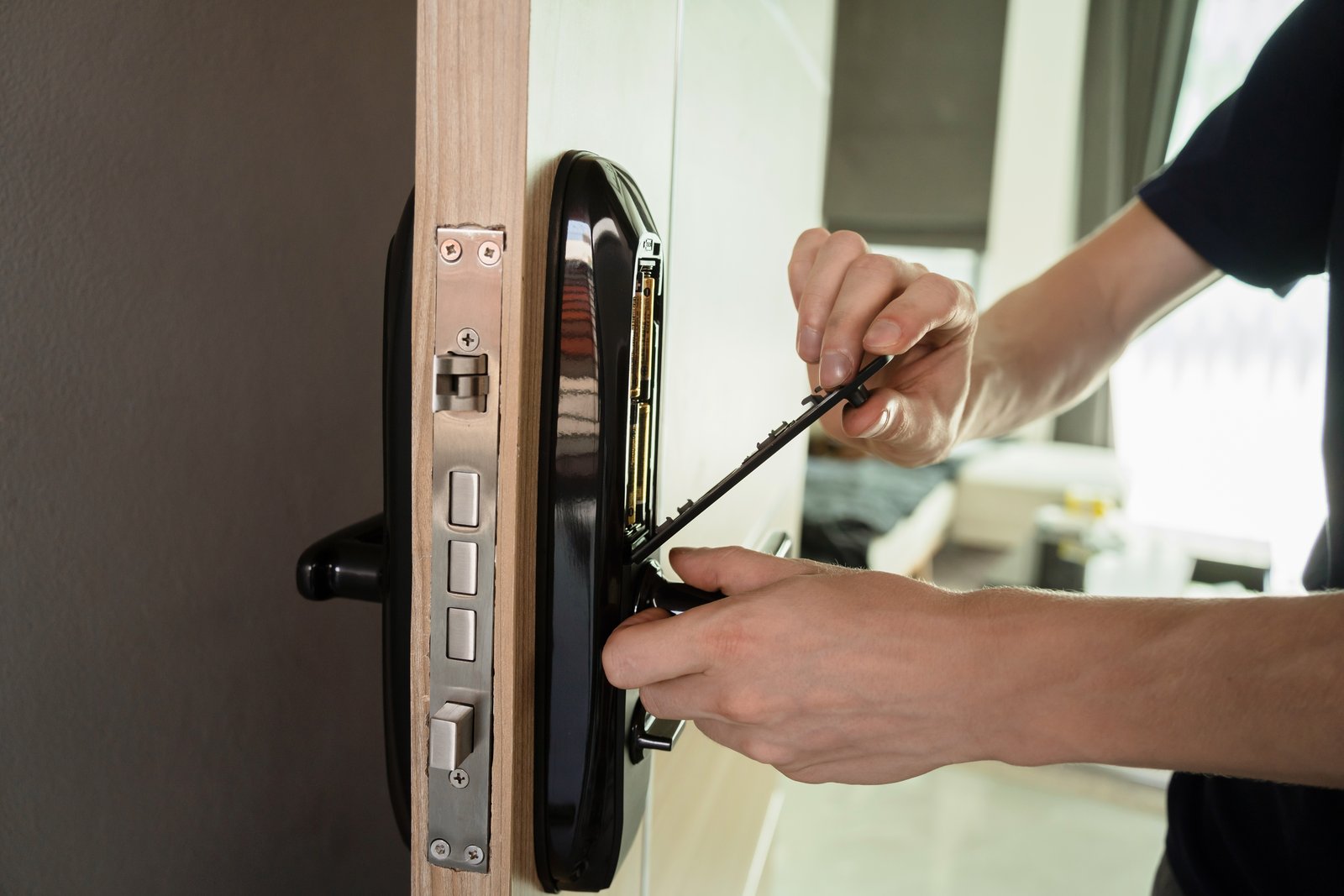 Hands repairing the battery compartment of a smart lock on a commercial premises
