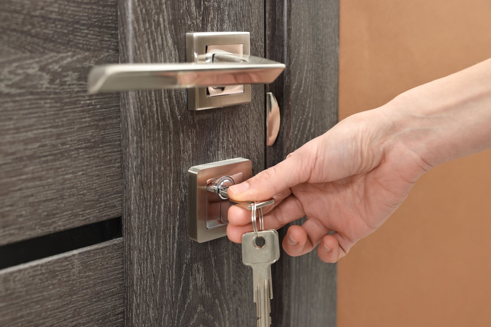 A hand turning a key in a modern door lock