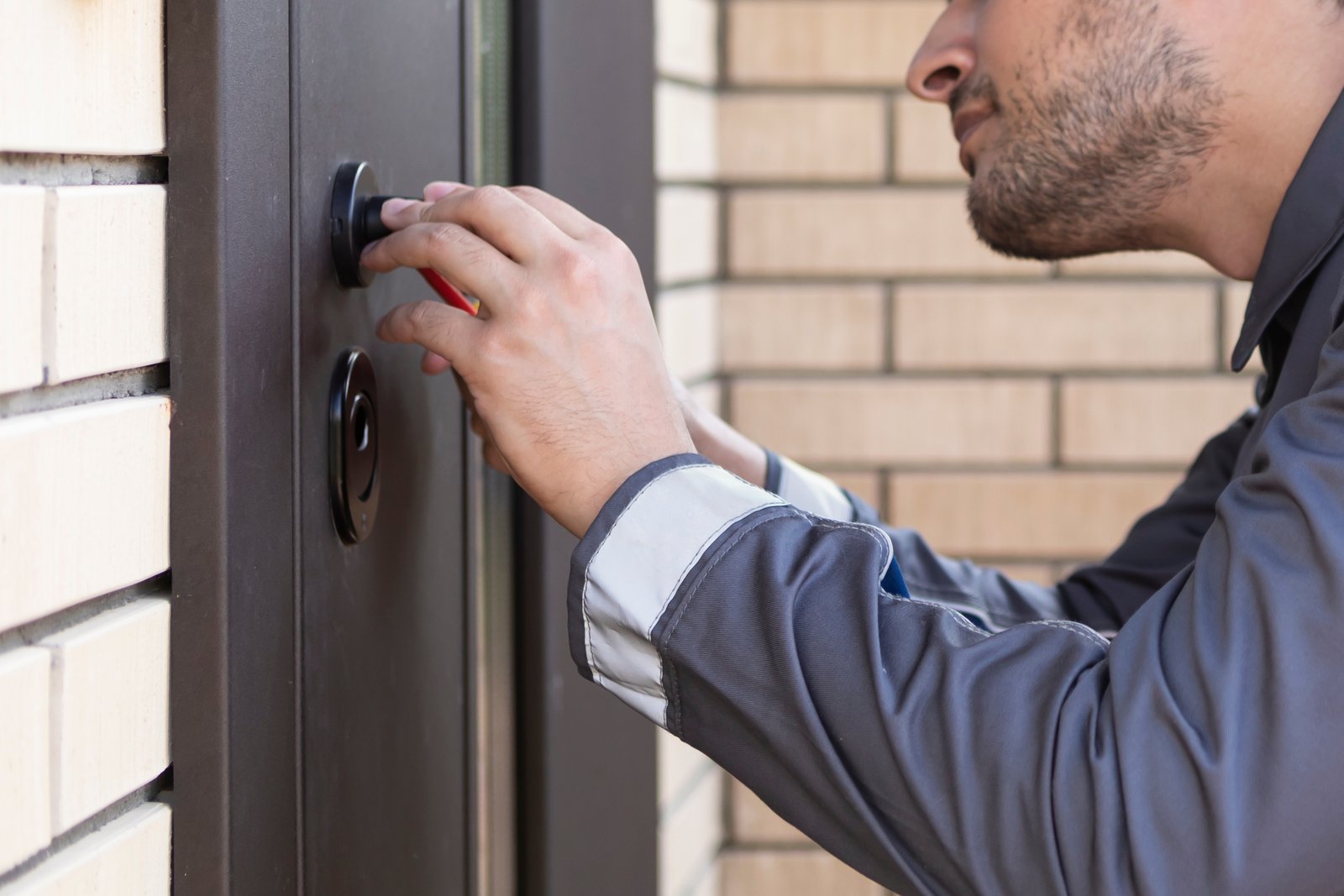 A locksmith working carefully on an exterior door lock
