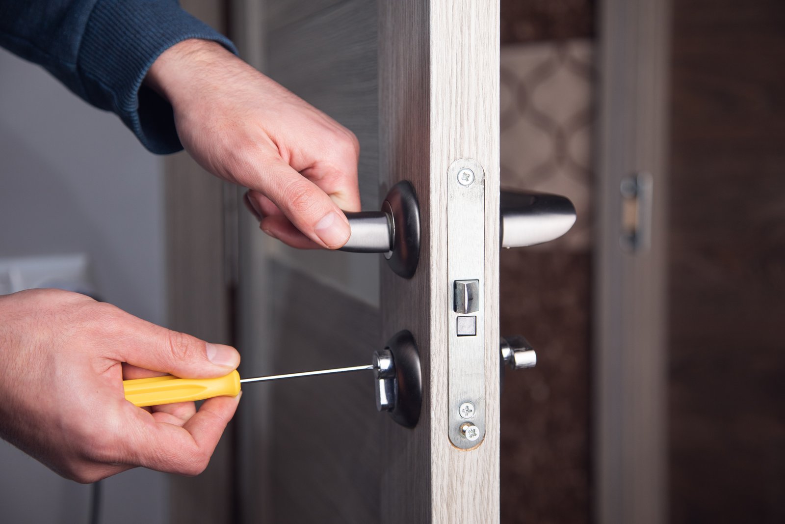 A hand fitting a mortice latch mechanism during a lock repair