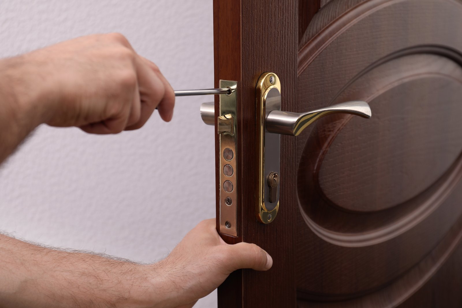 A hand fitting a handle-set lock to a solid commercial-style door