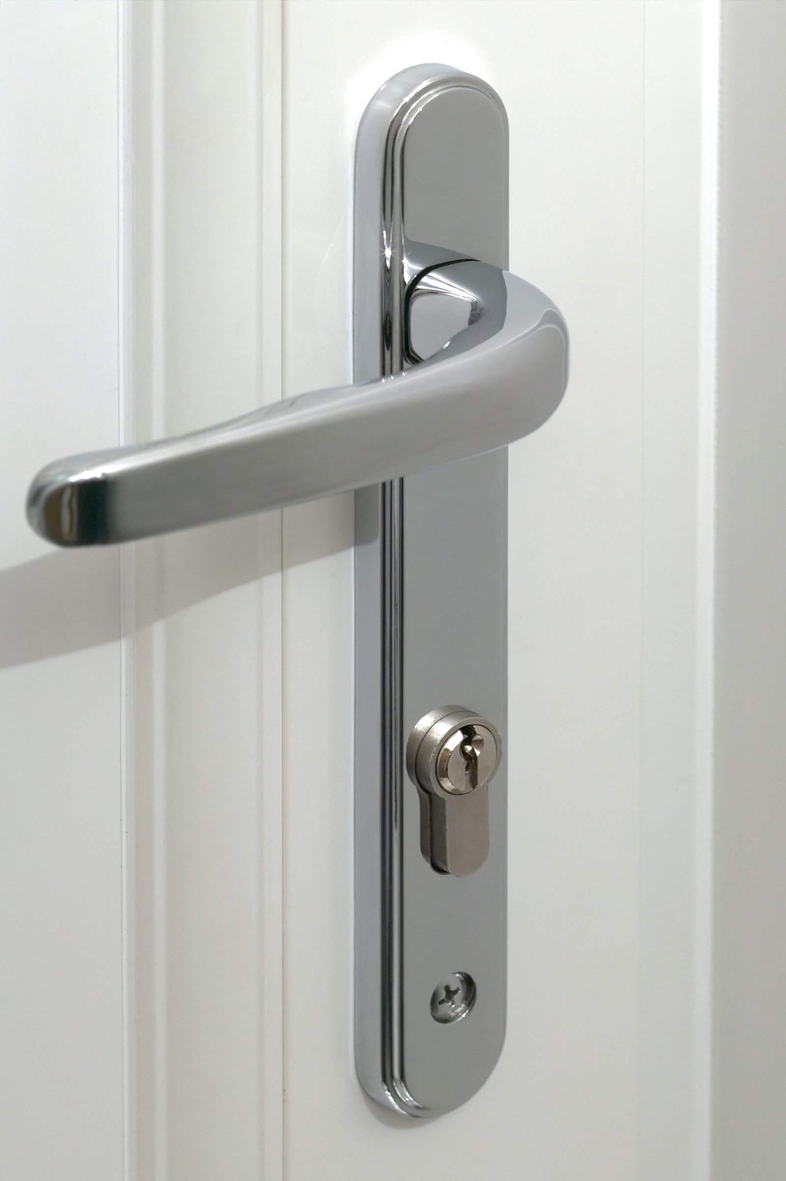 A close-up of a chrome multipoint door handle and cylinder lock on a white uPVC door