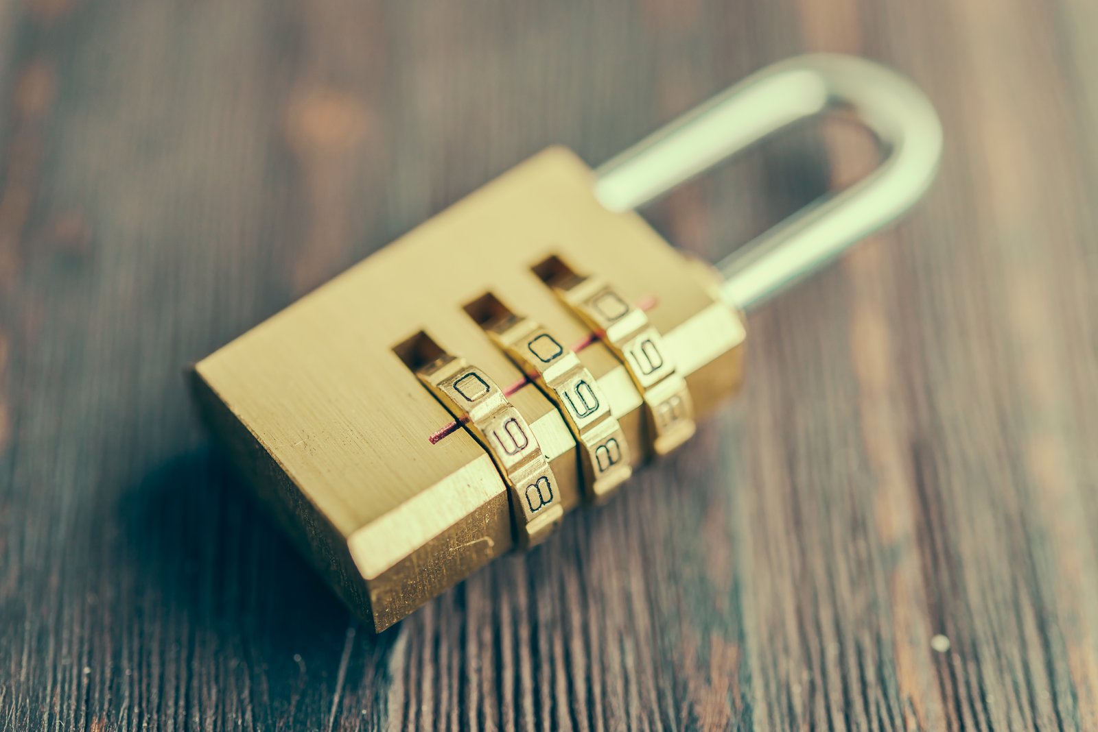 A brass combination padlock resting on a wooden surface