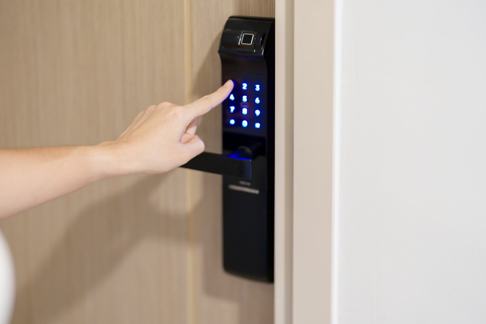 A hand entering a code on a smart lock keypad with a fingerprint scanner on a residential door