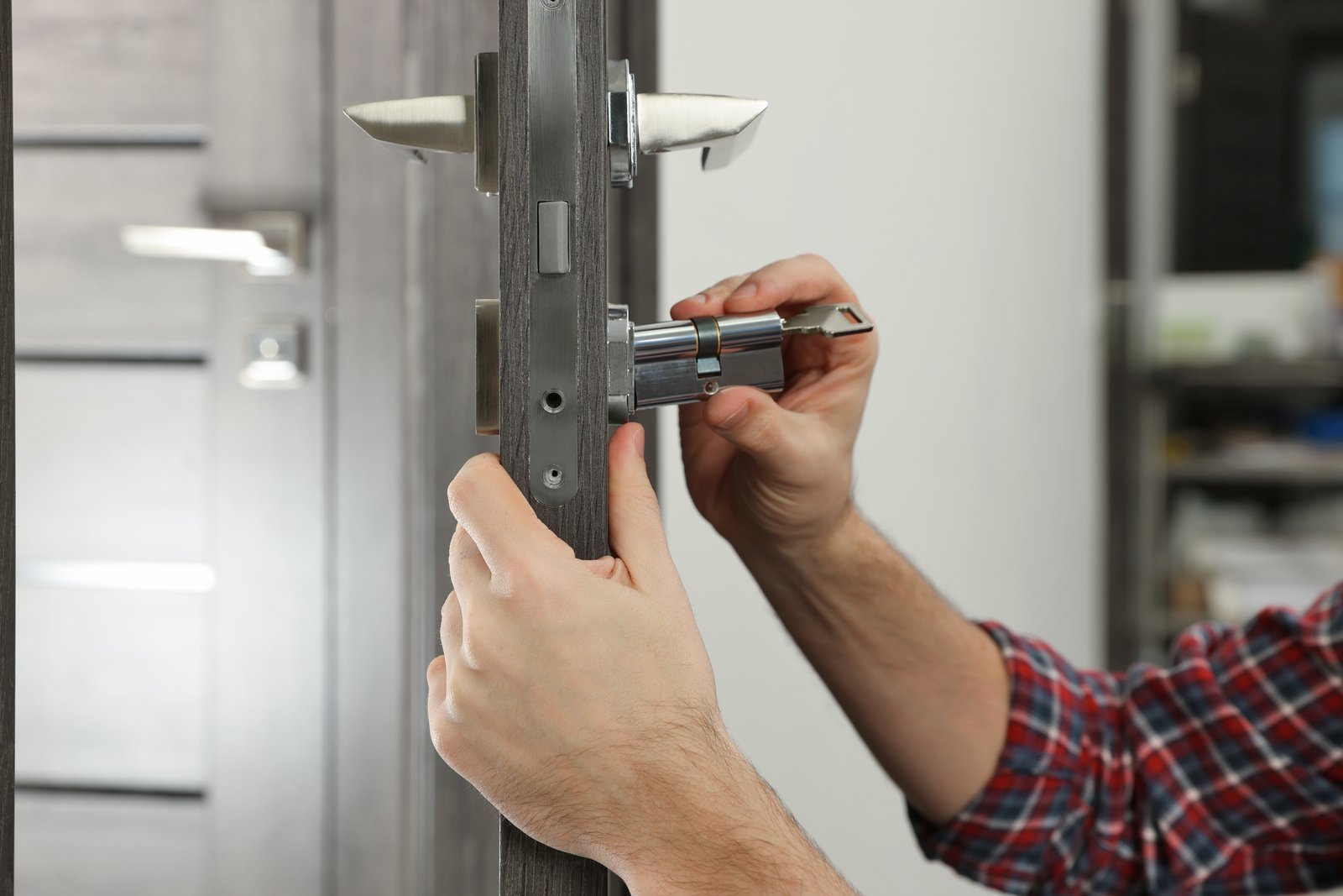 A hand fitting a euro cylinder lock into a residential door with a key inserted