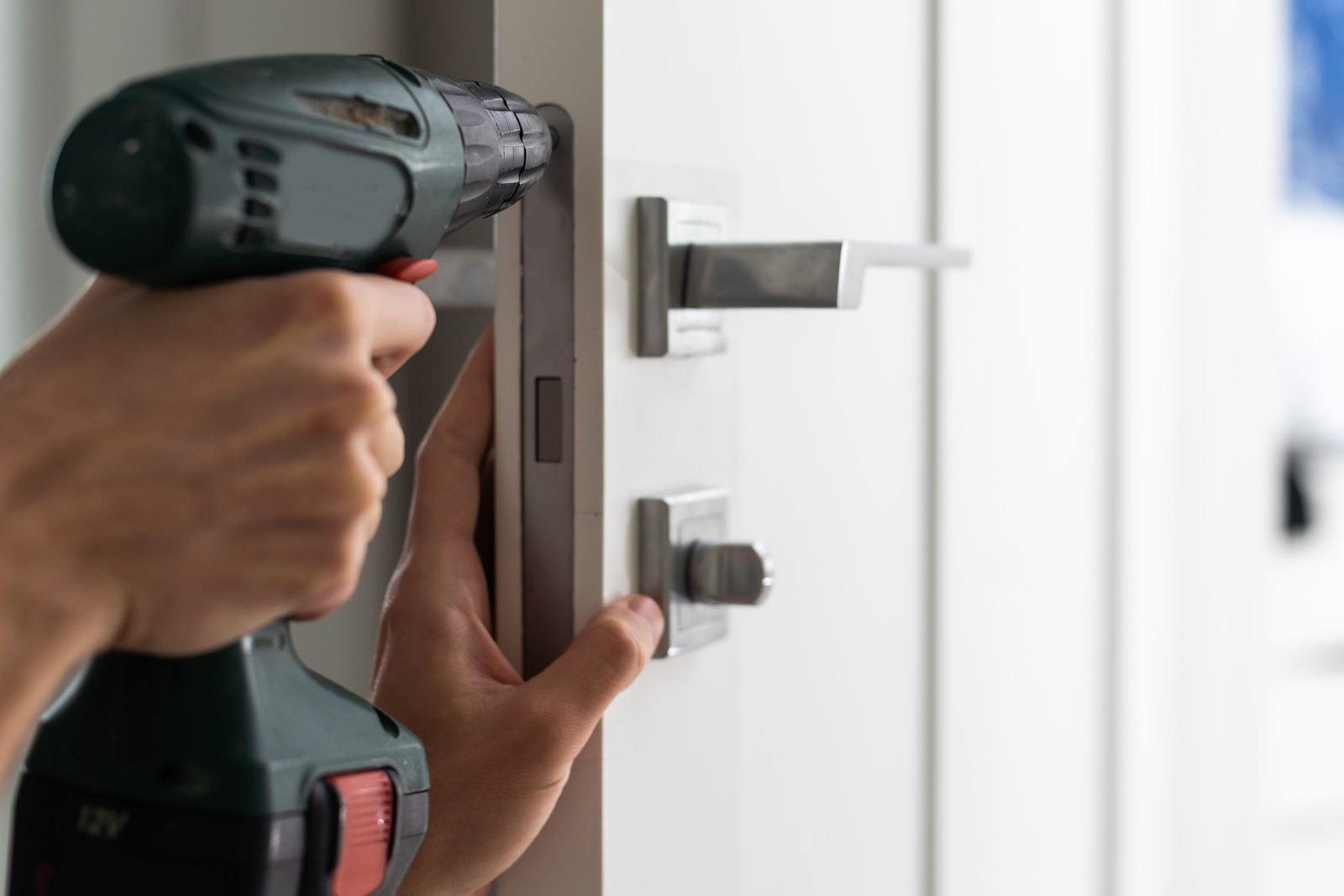 A hand using a drill to fit a thumbturn cylinder into a door