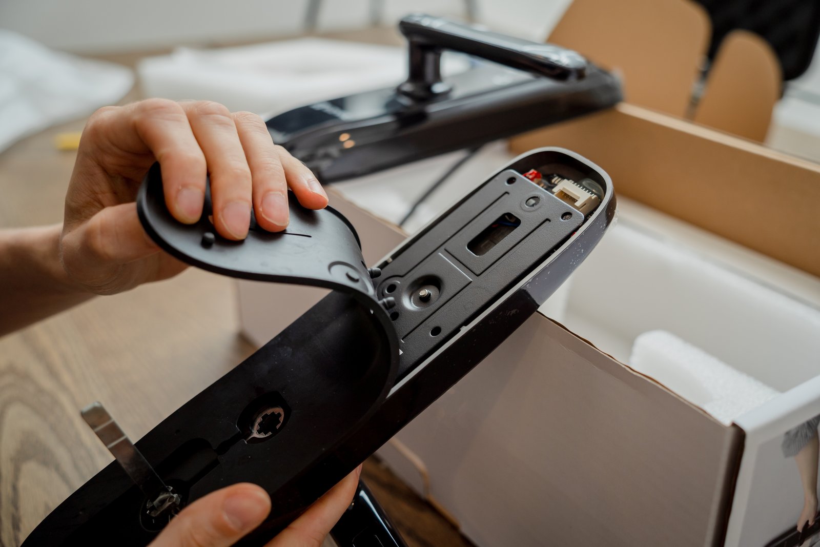A dismantled electronic door handle mechanism being assembled on a workbench