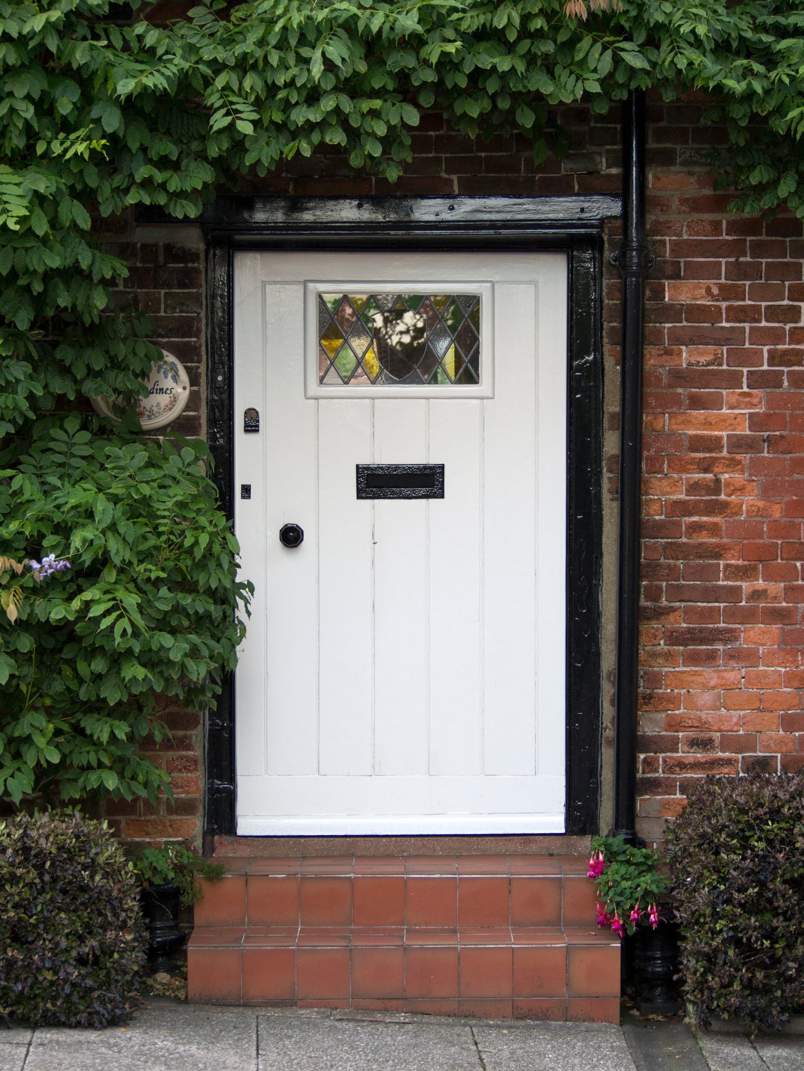 A period white panelled front door with stained glass on a red-brick terrace house