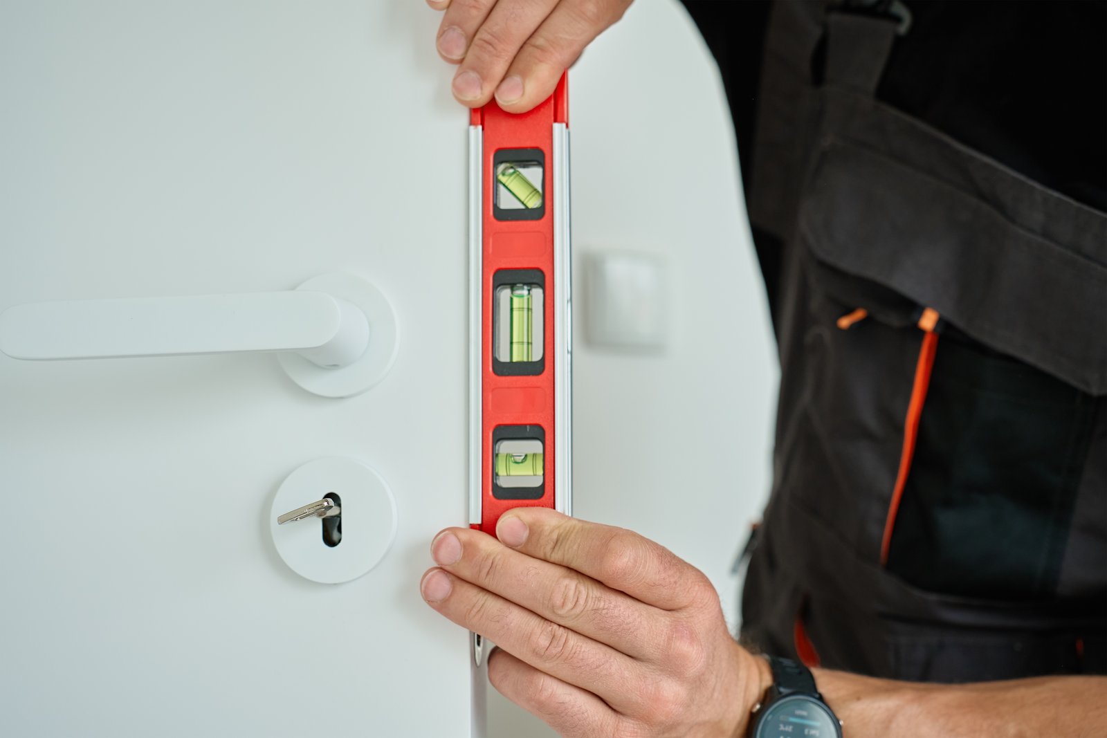 A tradesperson checking a modern door with a spirit level