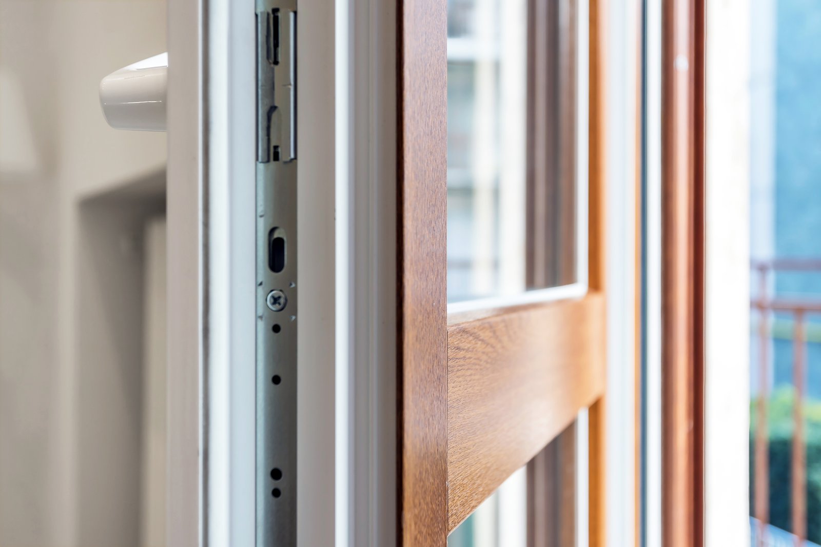 A hand fitting a hinge and lock strip into the edge of a glass-panelled wooden door