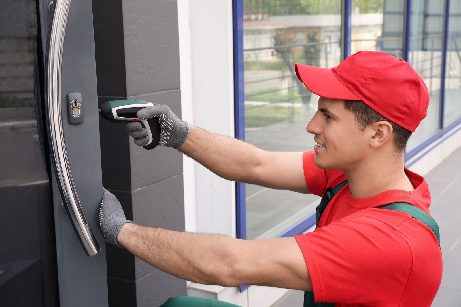 A locksmith fitting a lock to a commercial glass storefront door