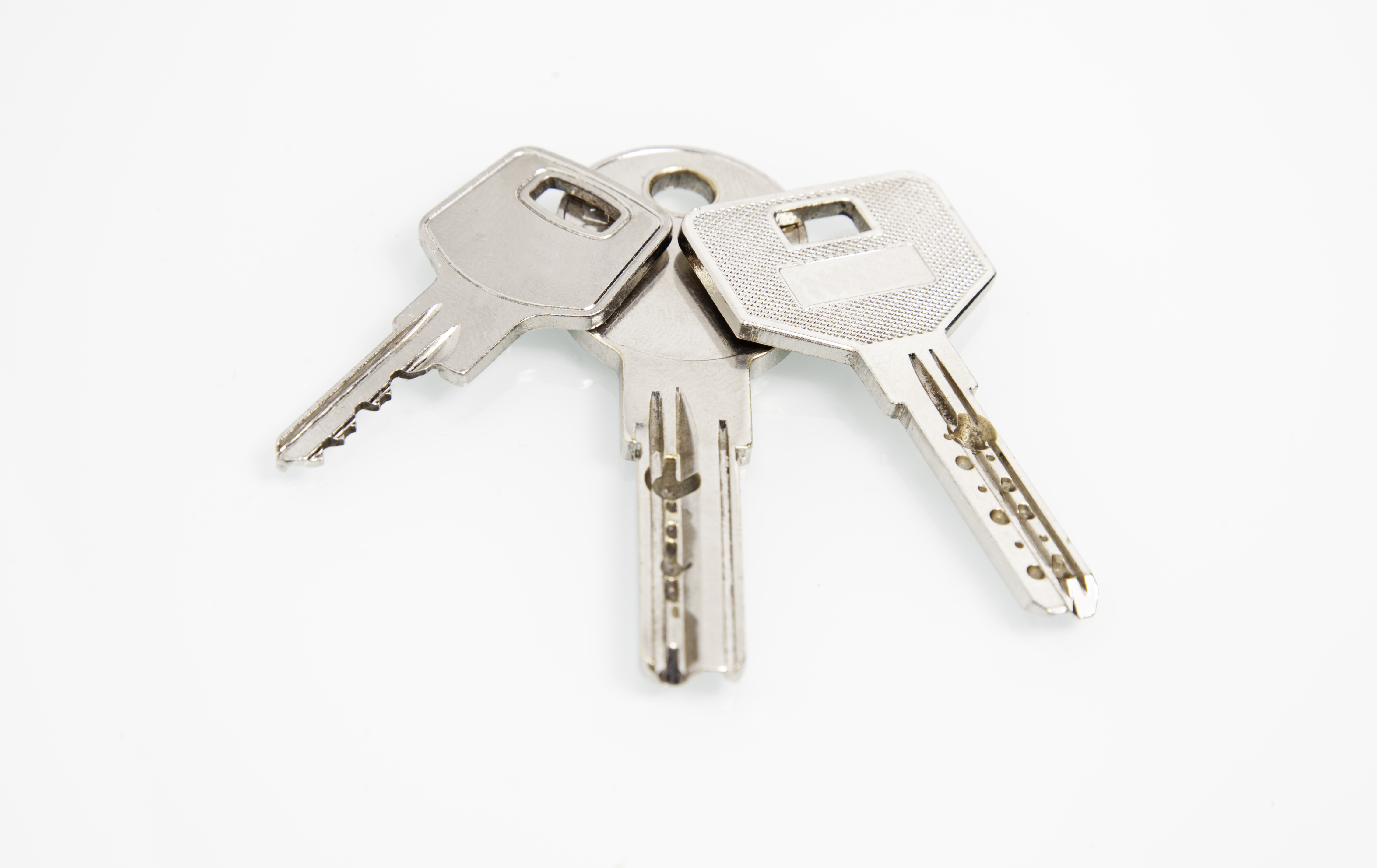 Three cut metal keys resting together on a plain surface